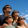 Famille portant des lunettes de protection pour éclipse solaire Grez Optic regardant le ciel